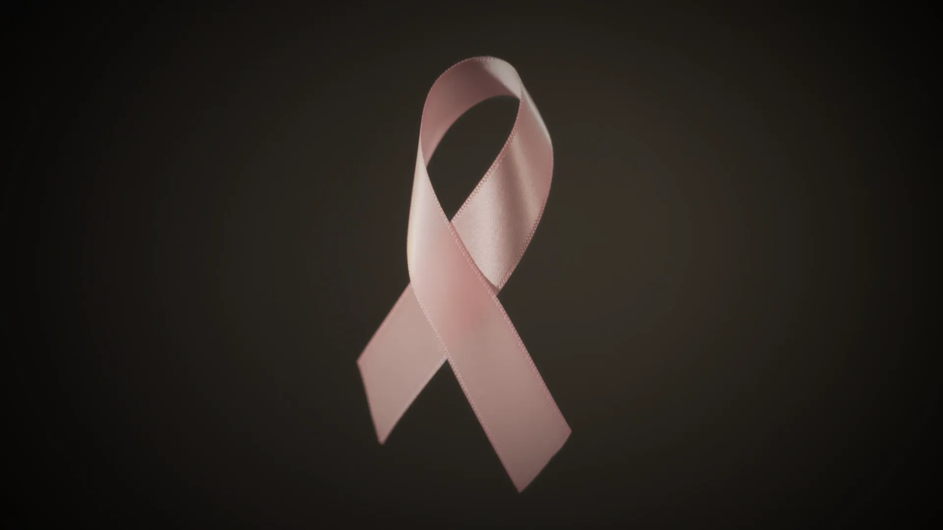 A pink ribbon on a dark background