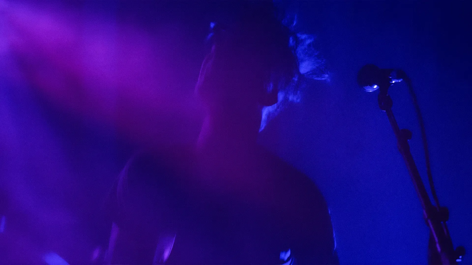 Stage lights and a microphone in purple haze